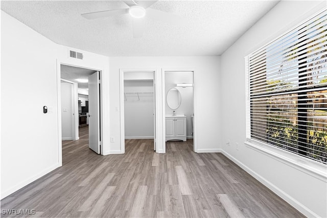 unfurnished bedroom with ceiling fan, a closet, a textured ceiling, and light wood-type flooring