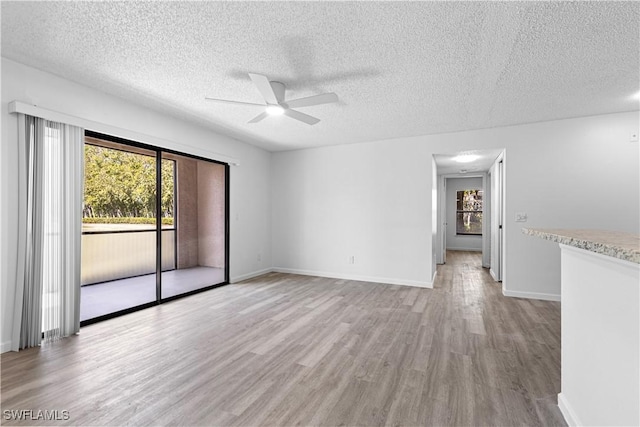 unfurnished room featuring ceiling fan, light hardwood / wood-style floors, and a textured ceiling