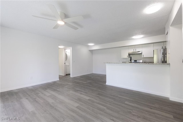 unfurnished living room featuring ceiling fan, dark hardwood / wood-style floors, and a textured ceiling