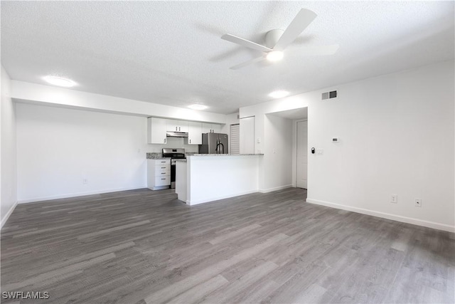 unfurnished living room featuring ceiling fan, dark hardwood / wood-style flooring, and a textured ceiling