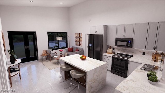 kitchen with black appliances, a sink, a kitchen breakfast bar, a kitchen island, and light tile patterned flooring