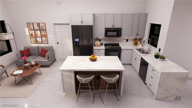 kitchen featuring a center island, a breakfast bar area, decorative backsplash, black appliances, and a sink