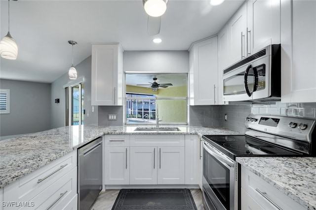 kitchen featuring stainless steel appliances, pendant lighting, and white cabinets