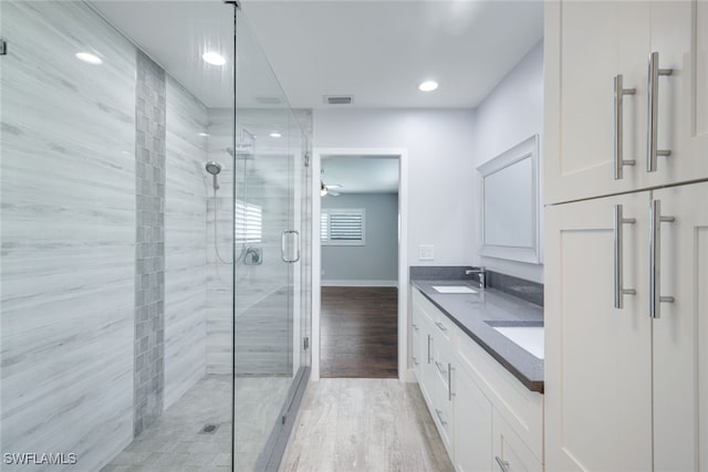 full bathroom with wood finished floors, a sink, visible vents, double vanity, and a stall shower