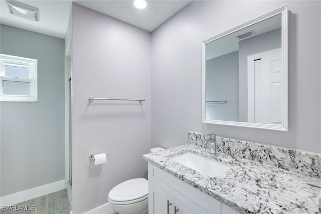 bathroom featuring visible vents, toilet, vanity, wood finished floors, and baseboards