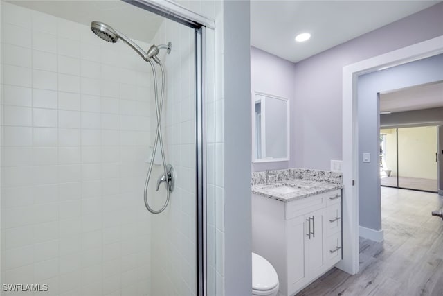 bathroom with toilet, vanity, a shower stall, and wood finished floors