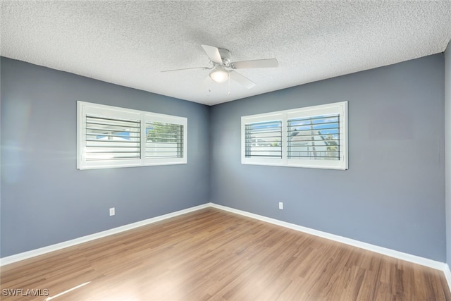 spare room featuring light wood-type flooring, ceiling fan, baseboards, and a textured ceiling