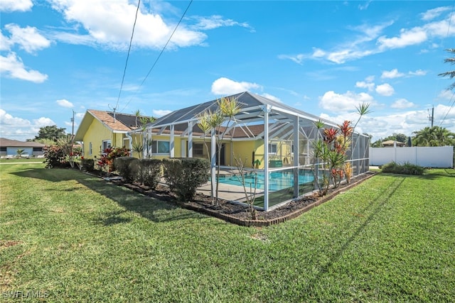 rear view of property featuring a lawn, fence, a lanai, and an outdoor pool