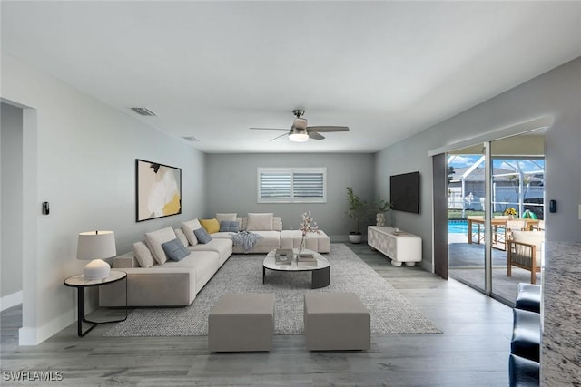 living area with a ceiling fan, baseboards, visible vents, and wood finished floors