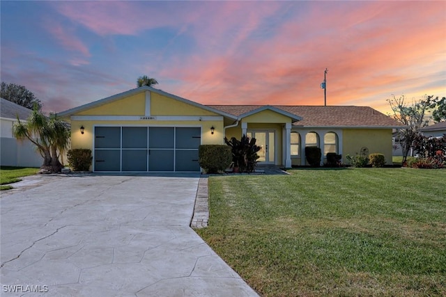 single story home with an attached garage, driveway, a front yard, and stucco siding