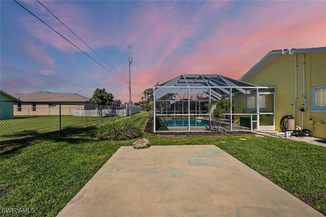 yard at dusk with glass enclosure, fence, an outdoor pool, and a patio