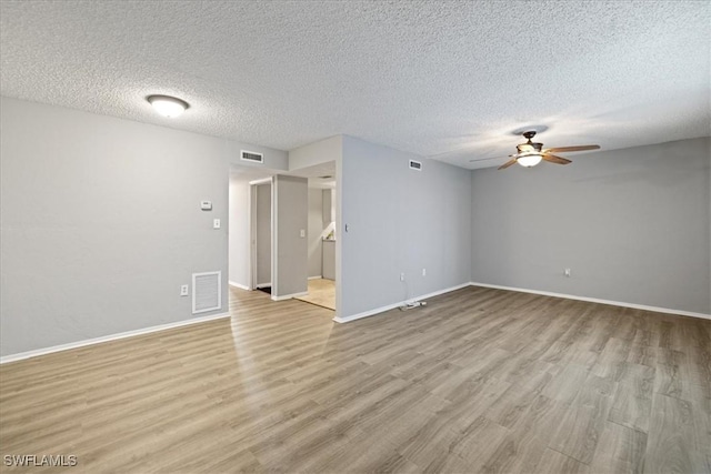 spare room with ceiling fan, a textured ceiling, and light wood-type flooring