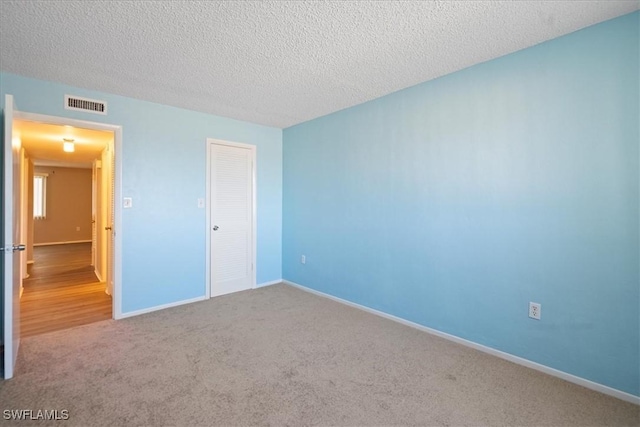 unfurnished bedroom featuring carpet floors, a textured ceiling, and a closet