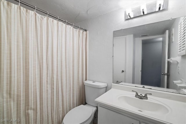 bathroom featuring vanity, walk in shower, and toilet