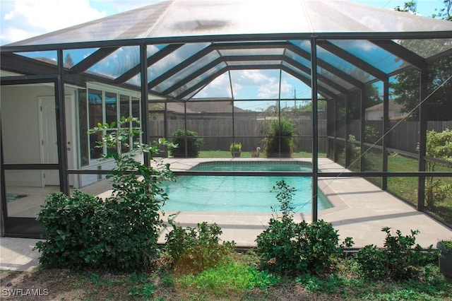 view of pool with a patio area and glass enclosure