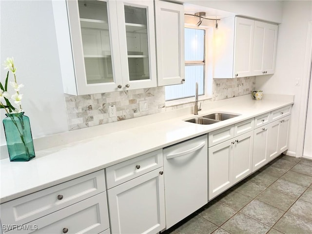 kitchen with white dishwasher, sink, decorative backsplash, and white cabinets