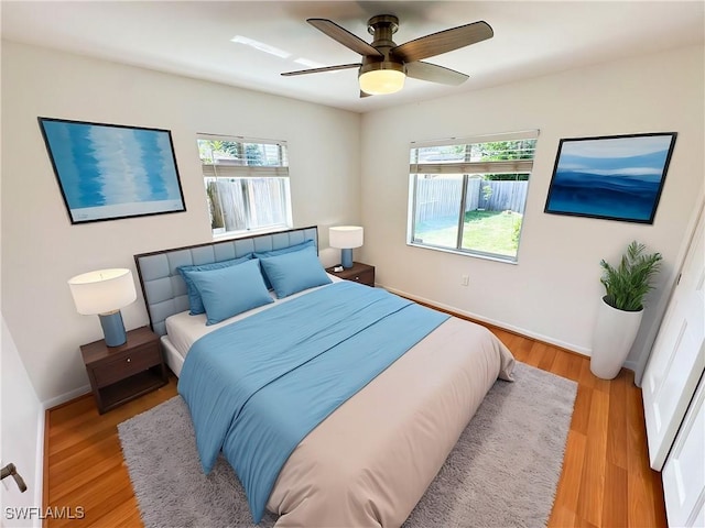 bedroom featuring ceiling fan, light hardwood / wood-style floors, and multiple windows