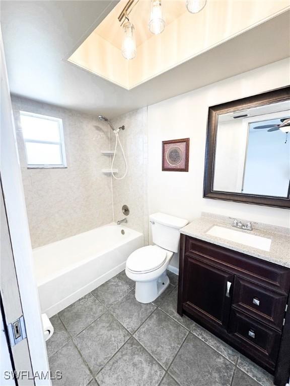 full bathroom featuring tiled shower / bath, vanity, ceiling fan, toilet, and tile patterned floors