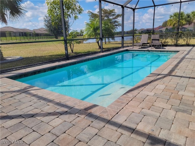 view of pool with a water view, a patio area, glass enclosure, and a lawn