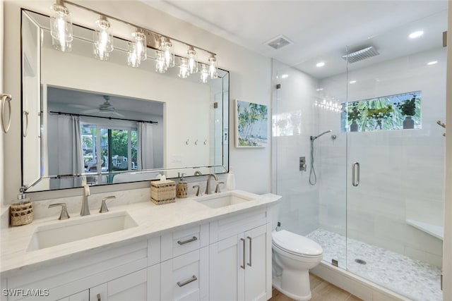 bathroom with ceiling fan, vanity, toilet, and a shower with door