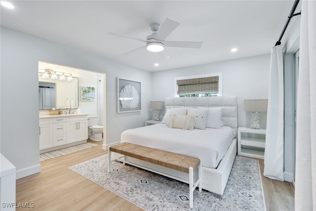 bedroom with ensuite bathroom, ceiling fan, and light wood-type flooring