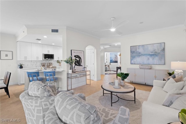 tiled living room with crown molding and ceiling fan