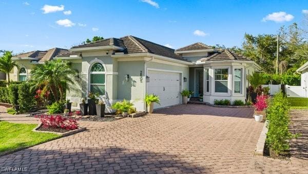 view of front facade featuring decorative driveway, an attached garage, and stucco siding