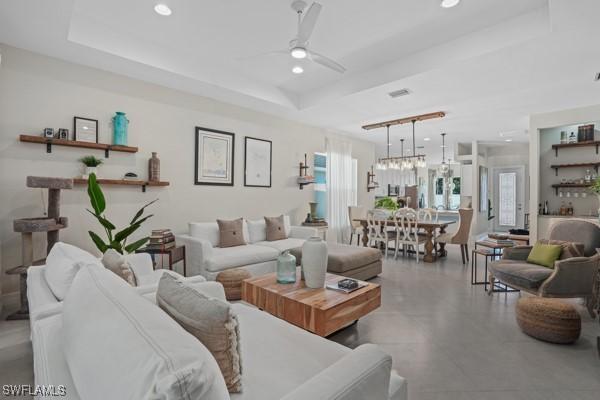 living room with recessed lighting, a tray ceiling, visible vents, and a ceiling fan