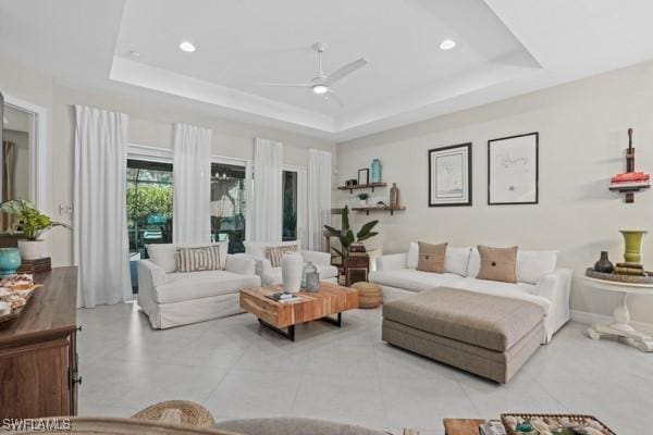 living area featuring recessed lighting, a raised ceiling, ceiling fan, and light tile patterned flooring