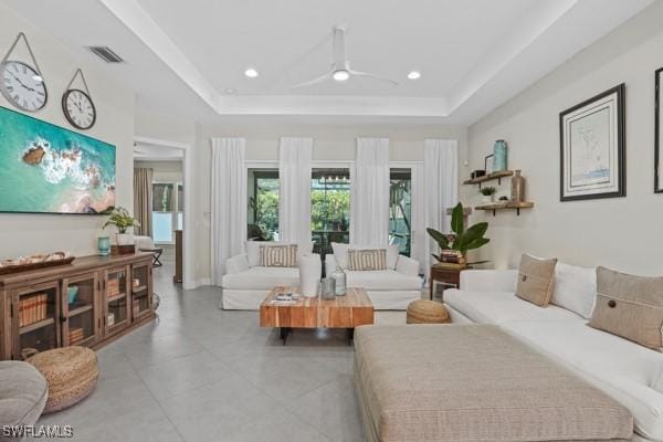 living area featuring a raised ceiling, recessed lighting, and visible vents