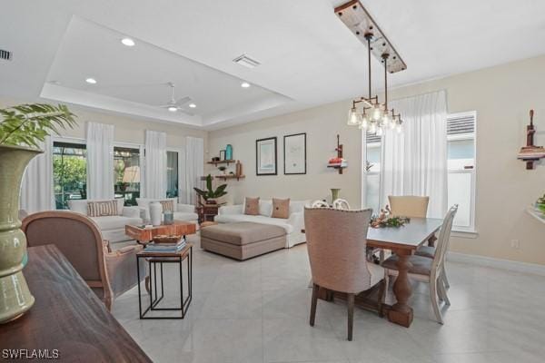 dining area featuring visible vents, baseboards, a raised ceiling, and a ceiling fan