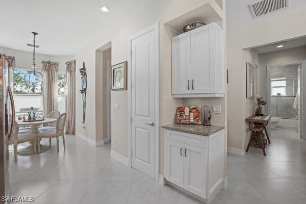 kitchen with stone counters, visible vents, plenty of natural light, and freestanding refrigerator