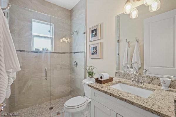 bathroom with toilet, a stall shower, and vanity