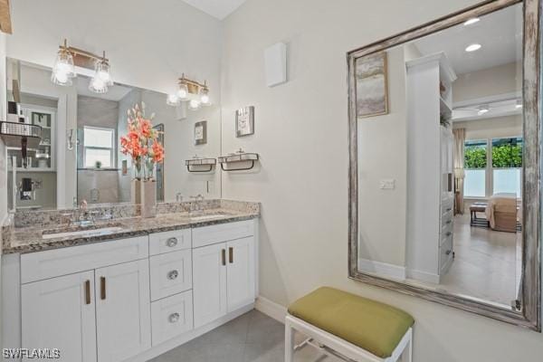 bathroom with tile patterned flooring, double vanity, baseboards, and a sink