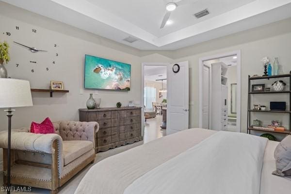 bedroom featuring visible vents, a raised ceiling, and ensuite bath