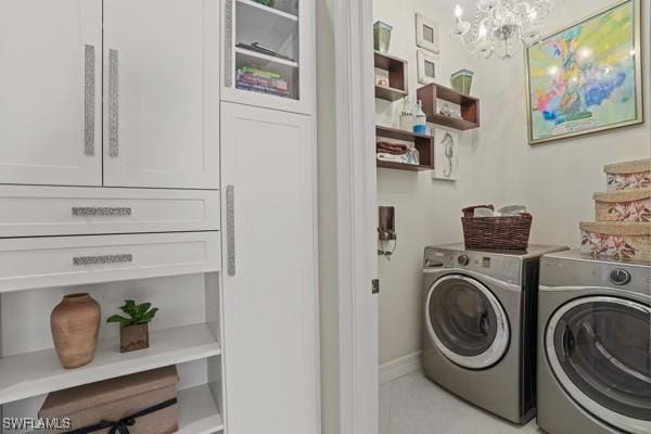 washroom featuring baseboards, cabinet space, separate washer and dryer, and a chandelier