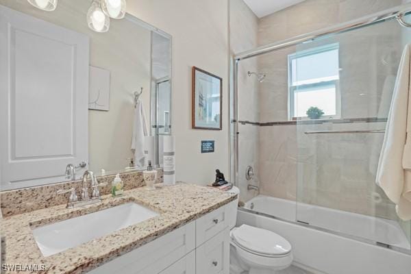 bathroom with vanity, toilet, and bath / shower combo with glass door