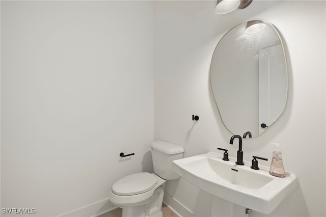 bathroom with baseboards, a sink, and toilet