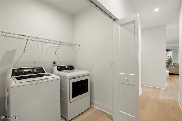 laundry area featuring baseboards, laundry area, separate washer and dryer, and light wood-style floors