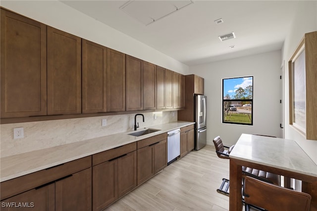 kitchen with visible vents, appliances with stainless steel finishes, a sink, light countertops, and backsplash