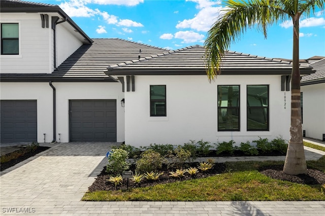 view of side of home featuring a tile roof, decorative driveway, and stucco siding