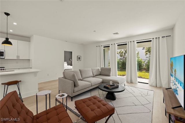 living room with light wood finished floors, baseboards, visible vents, and recessed lighting