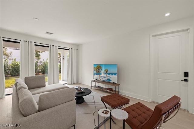 living room with recessed lighting, visible vents, light wood-style flooring, and baseboards