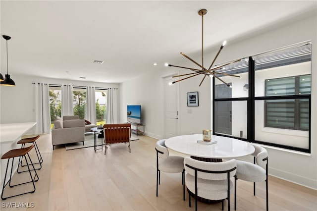 dining space with light wood-type flooring, visible vents, a notable chandelier, and baseboards