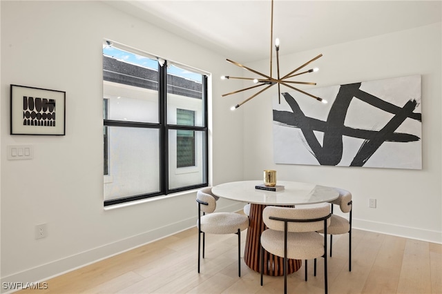 dining room featuring a chandelier, light wood-style flooring, and baseboards