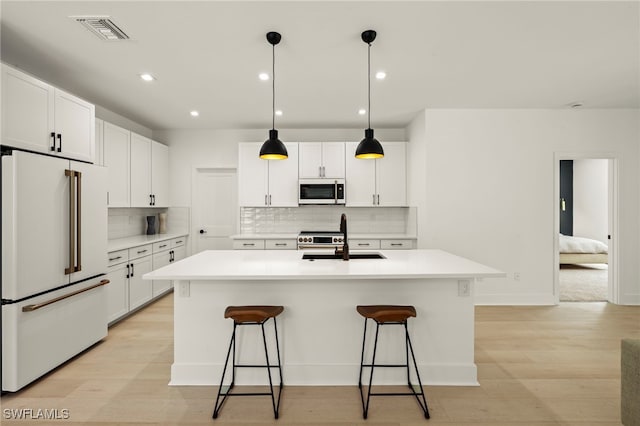 kitchen with visible vents, high end appliances, an island with sink, a breakfast bar area, and a sink