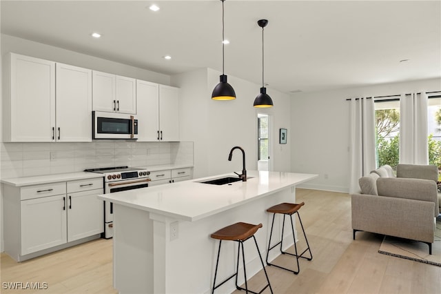 kitchen featuring electric stove, open floor plan, a sink, light wood-style floors, and backsplash