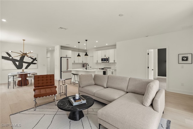 living room with visible vents, baseboards, light wood-style flooring, a chandelier, and recessed lighting