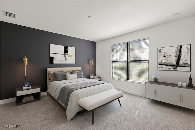 bedroom with baseboards, visible vents, and light colored carpet