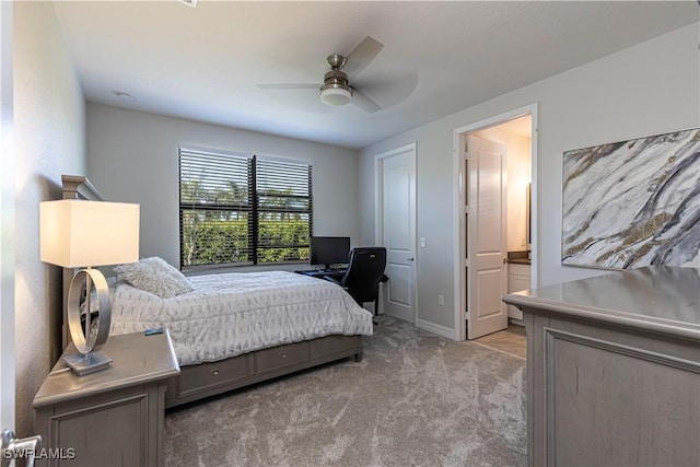 bedroom featuring light carpet, ceiling fan, ensuite bathroom, and baseboards